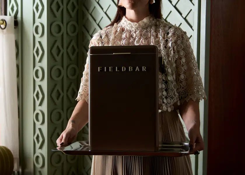 Person holding a tray with a 'FIELDBAR' sign in an indoor setting
